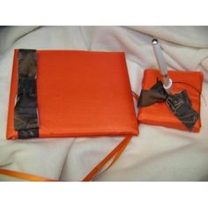 an orange bag with a bow on it sitting on top of a white bed sheet