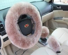 the interior of a car with a steering wheel cover and fuzzy pink fur on it