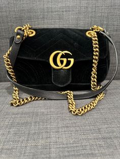 Elevate your style with this stunning Gucci shoulder bag. The black velvet exterior is accented with the iconic GG Marmont design, adding a touch of luxury to any outfit. The mini size is perfect for carrying your essentials, while the metallic hardware adds a touch of sophistication. This bag is a must-have for any fashion-forward woman and is sure to turn heads wherever you go. Authentic Gucci bag. Authenticity guaranteed. Happy to send more photos upon request! Elegant Black Gucci Bag, Velvet Gucci Bag, Luxury Gucci Bags With Metal Logo, Gucci Velvet Marmont Bag, Black Gucci Bag With Logo, Gg Marmont Mini, Gucci Shoulder Bag, Gg Marmont, Gucci Black