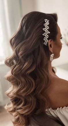 a woman with long hair wearing a tiara and pearls in her hair is looking off to the side