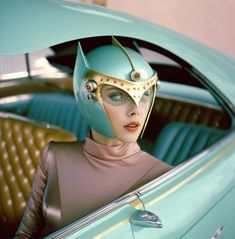 a woman in a blue car with a cat mask on it's head and eyes