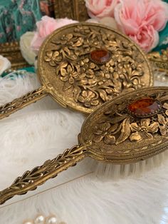 two antique hairbrushes sitting on top of a white fur covered floor next to flowers