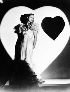 a woman standing in front of a large heart