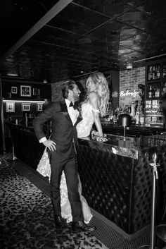 a man and woman standing in front of a bar