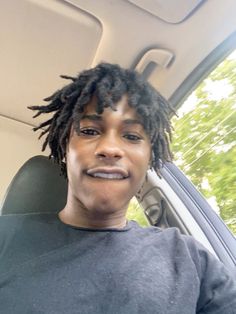 a woman with dreadlocks sitting in the back seat of a car looking at the camera