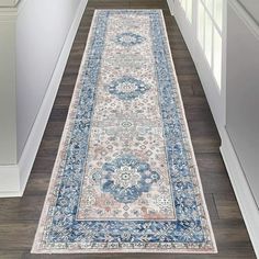 a long rug is on the floor next to a doorway with white walls and wooden floors