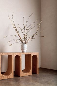 a vase sitting on top of a wooden block next to a planter filled with flowers