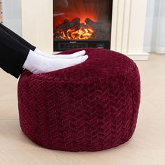 a person in white gloves is sitting on a bean bag chair by the fire place