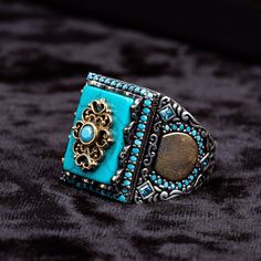 Turquoise Feroza Rectangle Silver Ring. Handmade in 925 sterling silver with Turquoise stone. On the ring, there is a big size turquoise - feroza stone covered with small Turquoise stones. The dimensions of the stone are 15 mm x 12 mm. The average weight of the Turquoise Feroza Rectangle Silver Ring is 19 gr. (depends on your ring size). The frame of the ring is plated with gold color rhodium. Classic and exclusive style. Stone Type: Turquoise - Feroza Stone Color: Blue Stone Dimensions: 15 mm x Luxury Turquoise Ring As A Gift, Luxury Sterling Silver Turquoise Ring Gift, Rectangular Sterling Silver Turquoise Ring As Gift, Handmade Silver Turquoise Ring With Rectangular Shape, Feroza Ring, Feroza Stone, Sterling Silver Turquoise Ring, Perfect As A Gift, Silver For Men, Nickel-free Blue Turquoise Ring In Sterling Silver