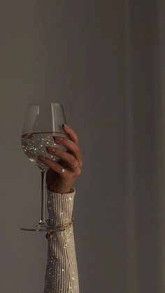 a woman holding a wine glass in her right hand and wearing a dress with sequins on it