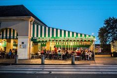 people sitting at tables in front of a restaurant