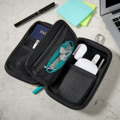 an open black case with ear buds and other items in it next to a laptop