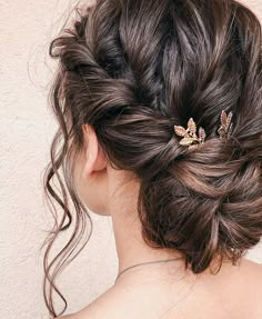 a woman with her hair in a low bun has two gold leaves pinned to it