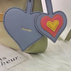 two heart shaped luggage tags attached to a handbag