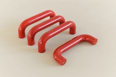 three red plastic handles on a white surface with no one in the photo looking at them