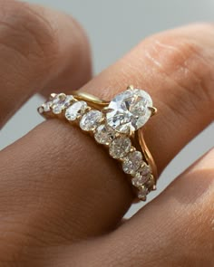 a woman's hand with a diamond ring on top of her finger and an engagement band