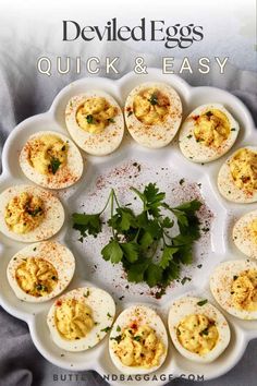 deviled eggs are arranged in a circle on a white platter with garnishes