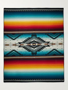 an image of a colorful blanket hanging on the wall in front of a white wall