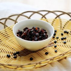 a bowl filled with raisins sitting on top of a yellow plate next to a wicker basket