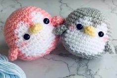 two small crocheted birds sitting next to each other on a marble counter top