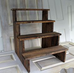 three wooden shelves sitting on top of each other in front of a white wall and door