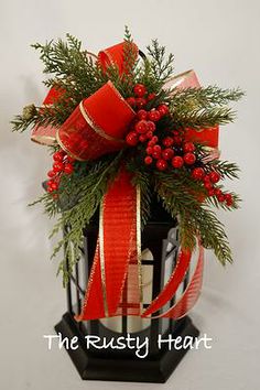 a red bow on top of a birdcage filled with berries and greenery