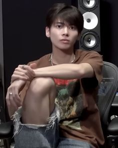 a young man sitting on top of a chair next to speakers