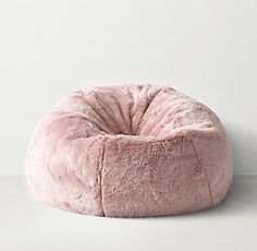 a pink bean bag chair sitting on top of a white floor next to a wall