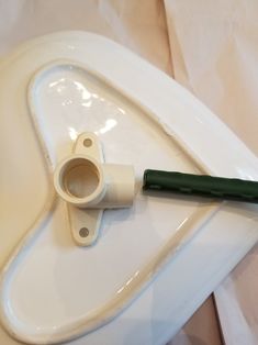 a white toilet with a green handle on the lid and an object attached to it