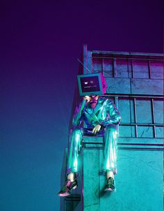 a man sitting on top of a tall building with a computer monitor in his head