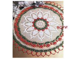 a crocheted doily is shown with red and green trimmings on it