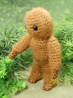 a stuffed teddy bear standing in front of some bushes and plants with eyes wide open