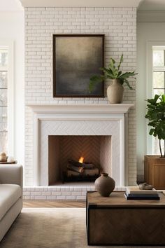 a living room with a white brick fireplace and potted plant on the mantel