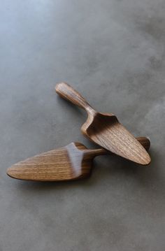 two wooden spoons sitting on top of a gray table next to each other,