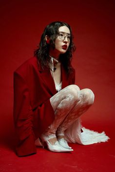 a woman with long hair and glasses is sitting on the floor wearing white tights