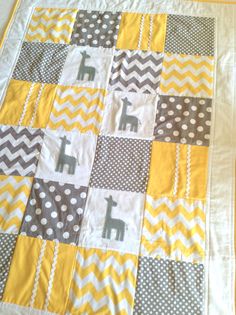 a yellow and gray baby quilt with giraffes on the front, chevron squares