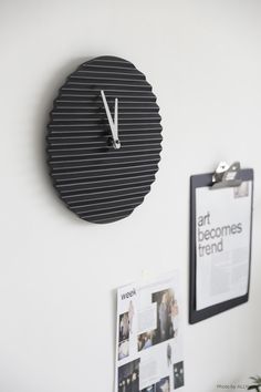 a black clock mounted to the side of a white wall next to a clipboard