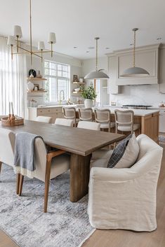 a large wooden table sitting in the middle of a living room next to a kitchen