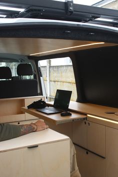 a man sitting at a desk in the back of a van with a laptop on it