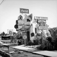 an old black and white photo of a man standing in front of a footlong restaurant