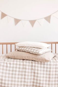 three pillows stacked on top of each other in front of a bed with gingham sheets