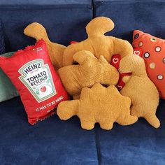 stuffed animals and pillows sitting on a blue couch in front of a pillow that says heinzz tomato ketchup