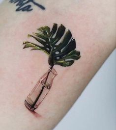 a tattoo with a plant in a bottle on the arm