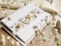 a card with hearts on it sitting on top of a wooden table next to some flowers