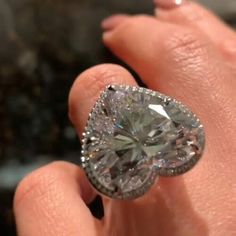 a close up of a person's hand holding a ring with a diamond in it