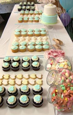 a table topped with lots of cupcakes next to a cake and candy bar