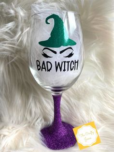 a wine glass with the words bad witch painted on it and a purple stemer