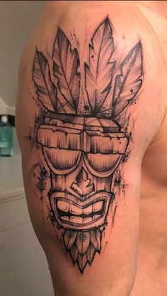 a man's arm with a tattoo on it that has a mask and leaves