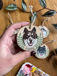 a hand holding a wooden ornament with an image of a dog on it