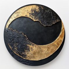 a black and gold circular object on a white surface with the moon in the center